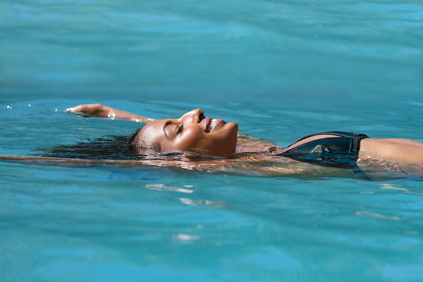 A woman smiling while floating on her back in a pool